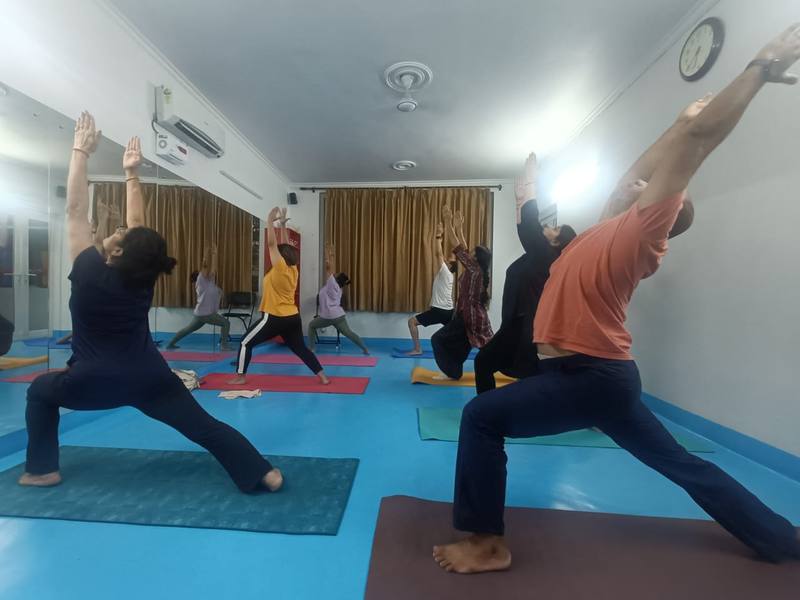 Group Warrior Pose class at Wellness Yoga Clinic